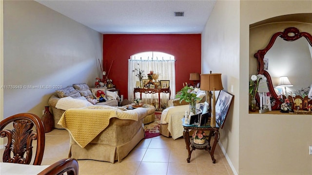 living area with visible vents, tile patterned flooring, and an accent wall