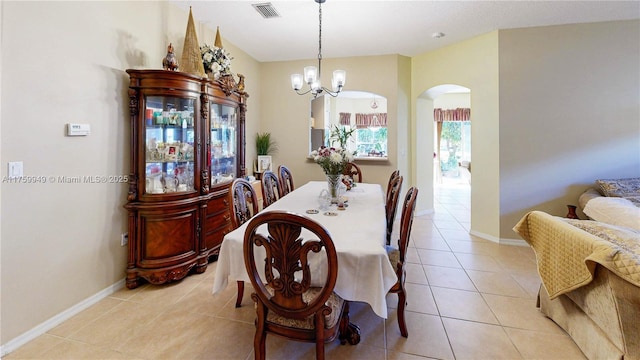 dining area with an inviting chandelier, light tile patterned floors, visible vents, baseboards, and arched walkways
