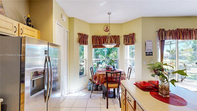 dining area featuring a textured ceiling, light tile patterned floors, and a healthy amount of sunlight