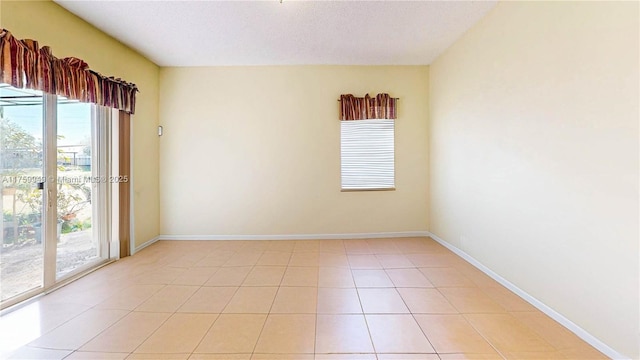 spare room with light tile patterned floors and baseboards