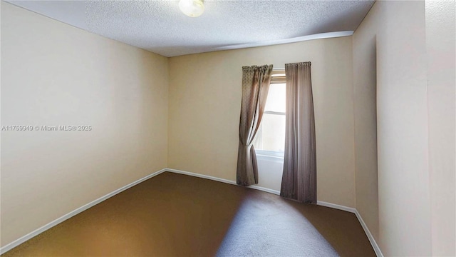 spare room with a textured ceiling, baseboards, and carpet floors