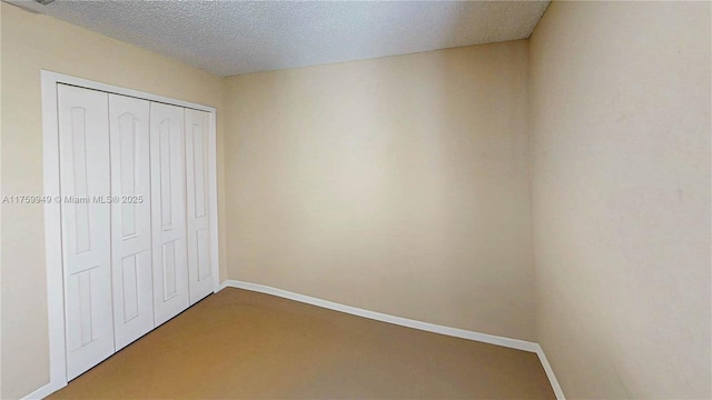 unfurnished bedroom featuring baseboards, a textured ceiling, a closet, and carpet