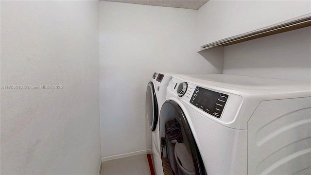 clothes washing area with baseboards, laundry area, and washer and dryer