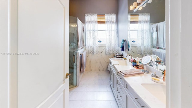 full bathroom with double vanity, tile patterned flooring, a stall shower, and a sink