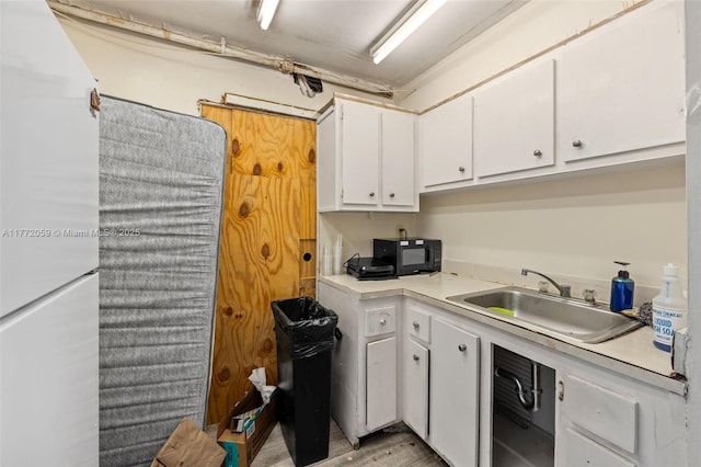 1035 W Ave Unit 507, Miami Beach, FL 33139 - kitchen featuring a sink, light countertops, white cabinets, and black microwave