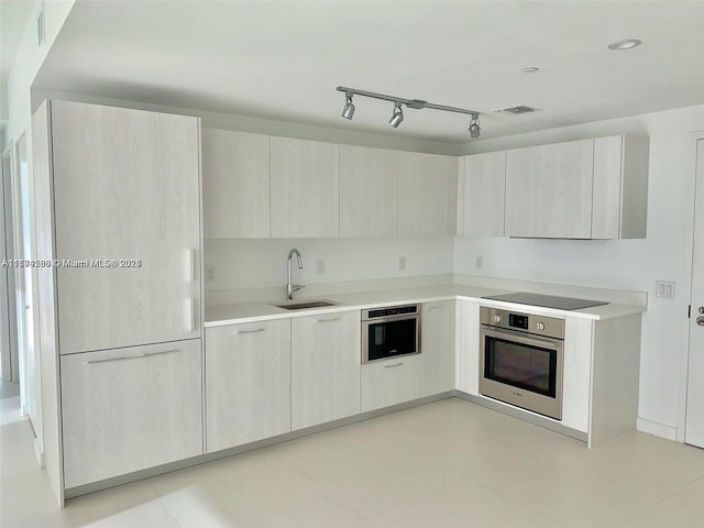 kitchen featuring light countertops, a sink, black electric stovetop, and stainless steel oven