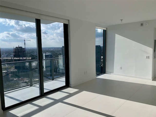 unfurnished room featuring a wealth of natural light, a wall of windows, a view of city, and tile patterned floors