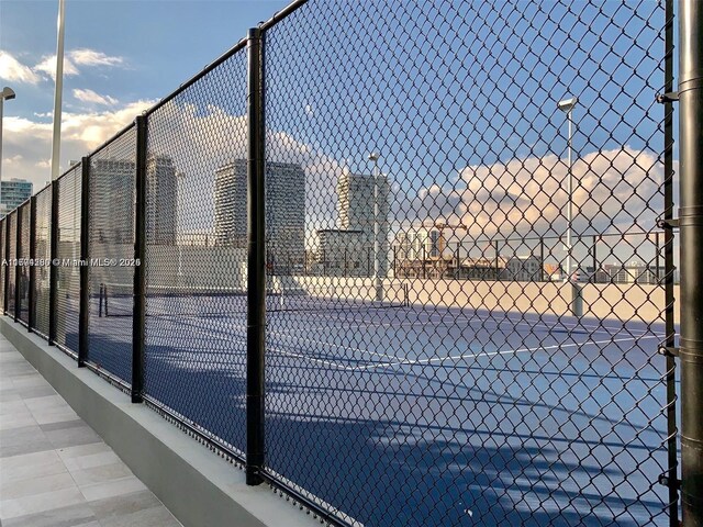 view of sport court with fence and a city view