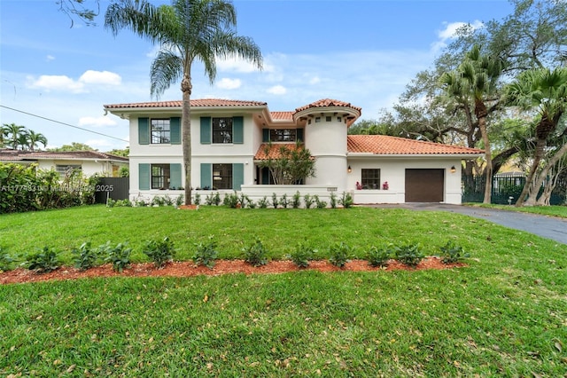 mediterranean / spanish-style home featuring stucco siding, driveway, a front yard, a tile roof, and a garage