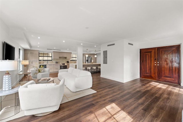 living room with electric panel, baseboards, wood finished floors, and recessed lighting