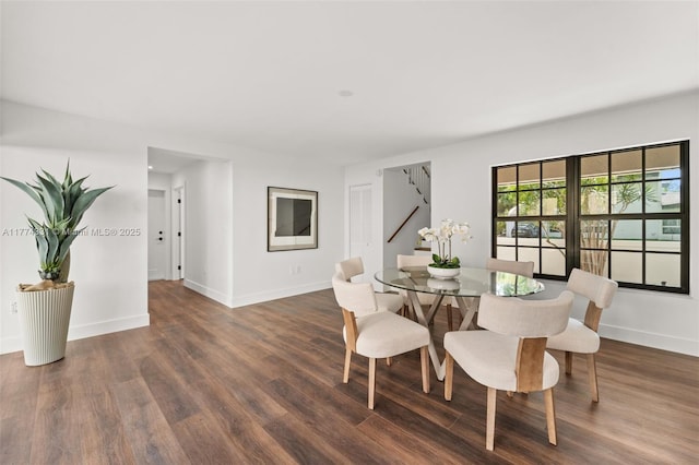 dining space with baseboards, wood finished floors, and stairs