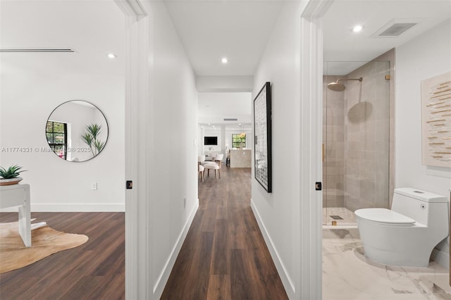 hall featuring baseboards, wood finished floors, visible vents, and recessed lighting