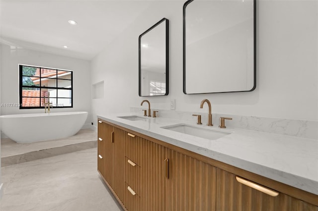 full bath featuring a freestanding bath, a sink, double vanity, and recessed lighting