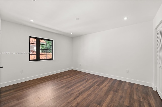 spare room with dark wood-type flooring, baseboards, and recessed lighting