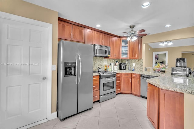 2343 SW 15th Pl, Deerfield Beach, FL 33442 - kitchen with a peninsula, stainless steel appliances, light tile patterned flooring, and brown cabinets