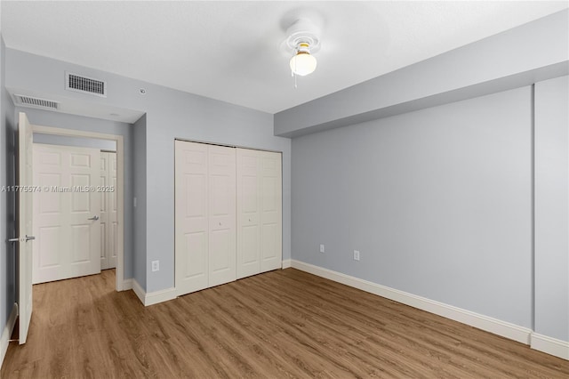 unfurnished bedroom with wood finished floors, baseboards, a closet, and ceiling fan