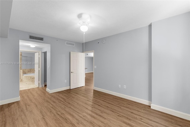 unfurnished bedroom with light wood-style floors, baseboards, and connected bathroom