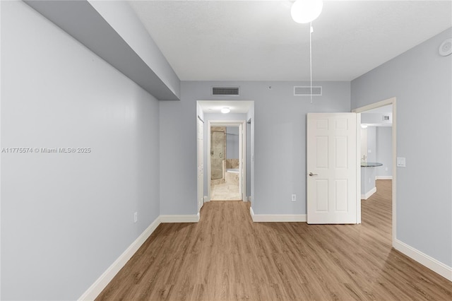 unfurnished bedroom featuring wood finished floors, baseboards, and ensuite bath