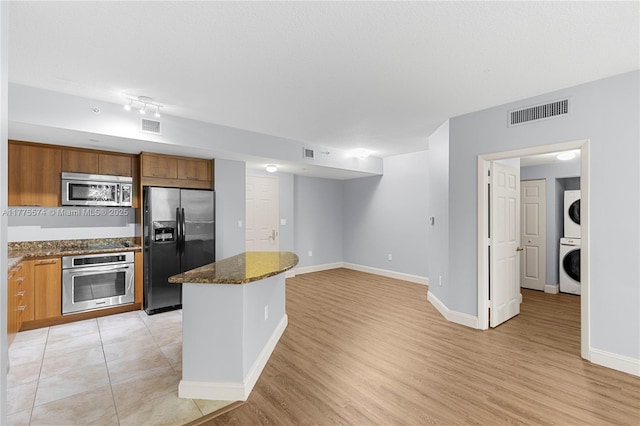 510 NW 84th Ave Unit 242, Plantation, FL 33324 - kitchen featuring stainless steel appliances, estacked washer and dryer, a center island, dark stone counters, and light wood-style floors