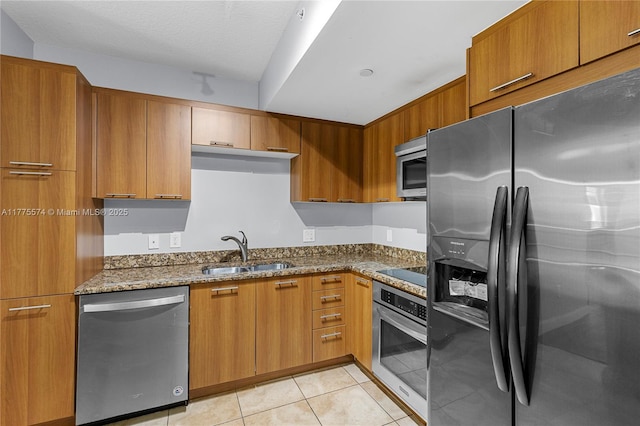 510 NW 84th Ave Unit 242, Plantation, FL 33324 - kitchen with stainless steel appliances, a sink, dark stone counters, light tile patterned floors, and brown cabinets