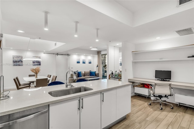kitchen featuring white cabinetry, a sink, stainless steel dishwasher, and open floor plan
