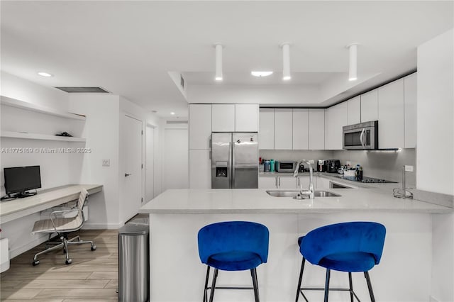 kitchen featuring light countertops, a sink, a kitchen bar, a peninsula, and stainless steel appliances