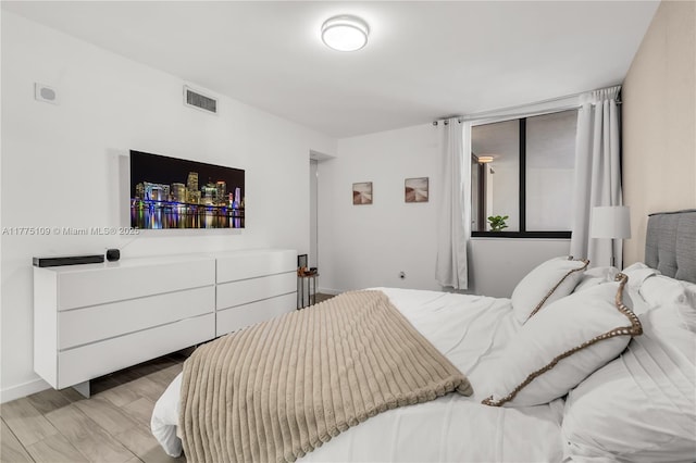 bedroom with baseboards, light wood-style floors, and visible vents