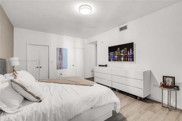 bedroom with light wood finished floors, baseboards, and visible vents