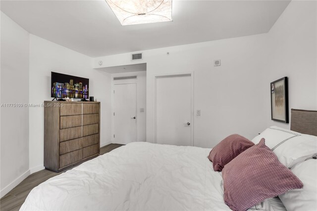 bedroom with baseboards, visible vents, and wood finished floors