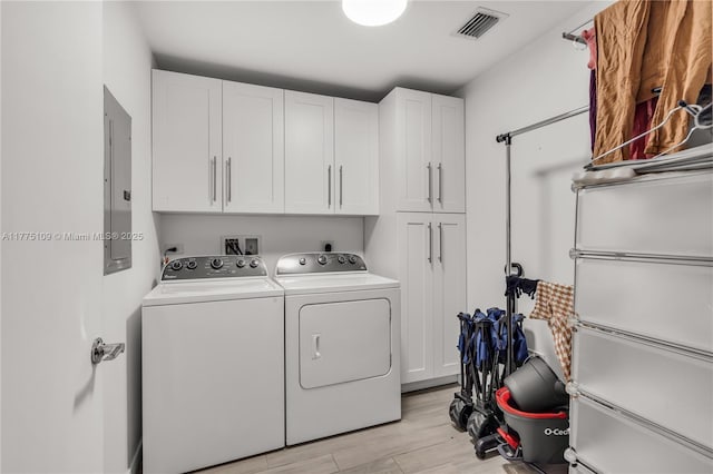 washroom with washer and clothes dryer, light wood finished floors, visible vents, cabinet space, and electric panel