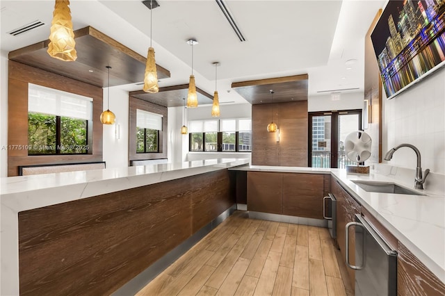 kitchen featuring visible vents, light wood-style flooring, modern cabinets, a sink, and light stone counters