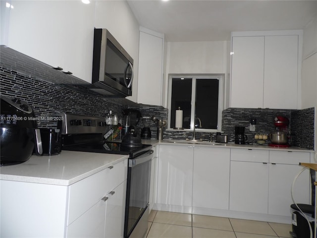 3491 Palm Ave, Hialeah, FL 33012 - kitchen featuring appliances with stainless steel finishes, a sink, backsplash, light tile patterned flooring, and white cabinetry