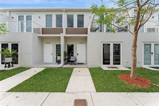 exterior space with a front lawn, stucco siding, and french doors