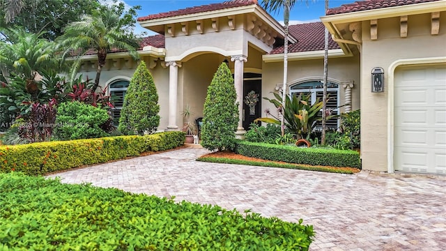 view of front of home featuring a tiled roof, stucco siding, a garage, and driveway