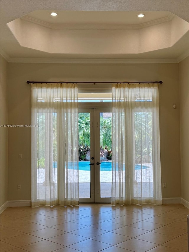 doorway to outside featuring french doors, a raised ceiling, tile patterned floors, ornamental molding, and baseboards