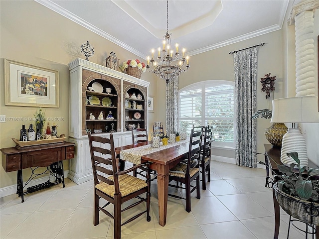 dining space with light tile patterned floors, a tray ceiling, a chandelier, ornamental molding, and baseboards