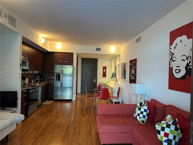 living area featuring visible vents and wood finished floors