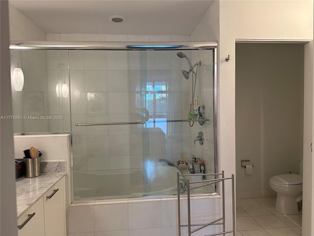full bath with vanity, tile patterned floors, a tile shower, and toilet