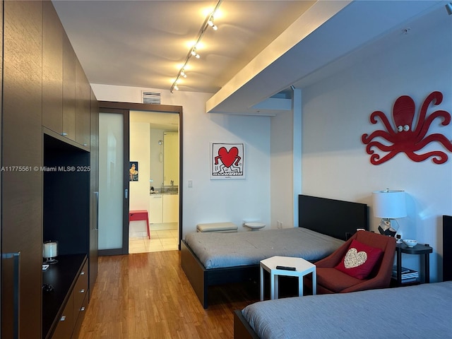bedroom featuring track lighting, wood finished floors, and visible vents
