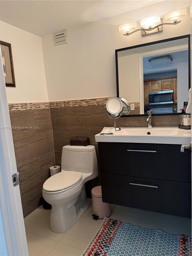 1901 Brickell Ave Unit B804, Miami, FL 33129 - half bathroom with tile patterned flooring, vanity, tile walls, and wainscoting