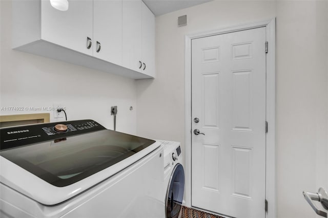 clothes washing area featuring washing machine and clothes dryer and cabinet space