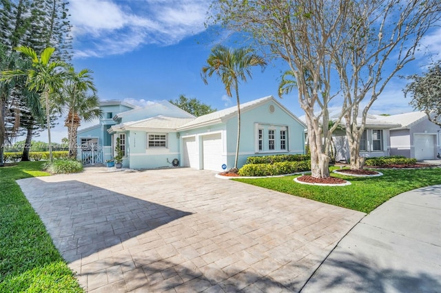 ranch-style house with a garage, a front yard, decorative driveway, and stucco siding