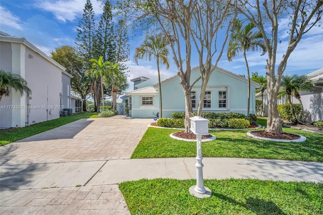 view of front of house featuring concrete driveway, a front yard, cooling unit, and stucco siding