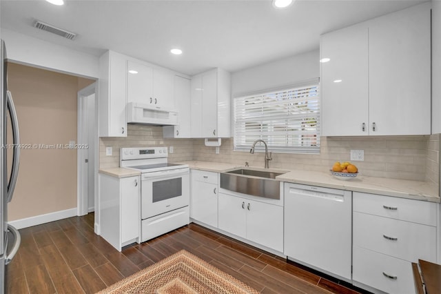 kitchen featuring white appliances, a sink, dark wood-style floors, white cabinets, and recessed lighting