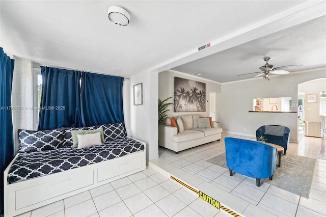 tiled living room featuring arched walkways, a ceiling fan, visible vents, and baseboards
