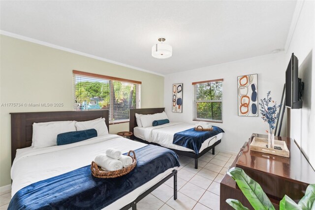 bedroom featuring baseboards, light tile patterned flooring, ornamental molding, and multiple windows