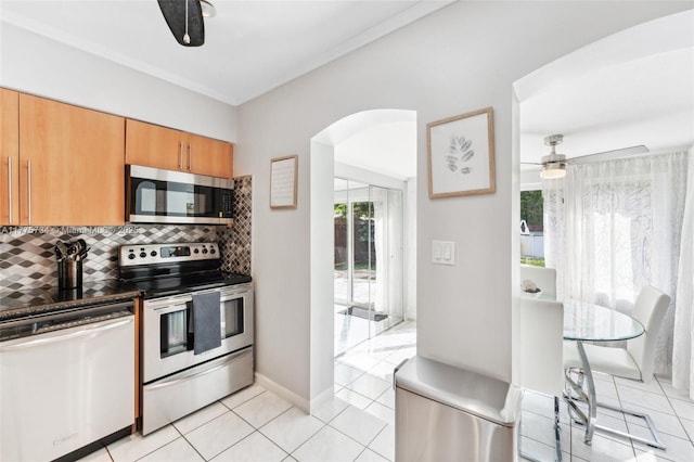 kitchen featuring light tile patterned floors, arched walkways, tasteful backsplash, appliances with stainless steel finishes, and ceiling fan