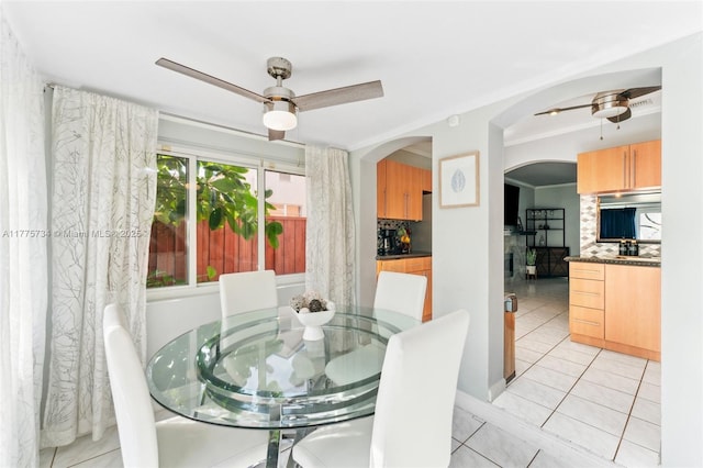 dining room with ceiling fan, arched walkways, light tile patterned flooring, and visible vents