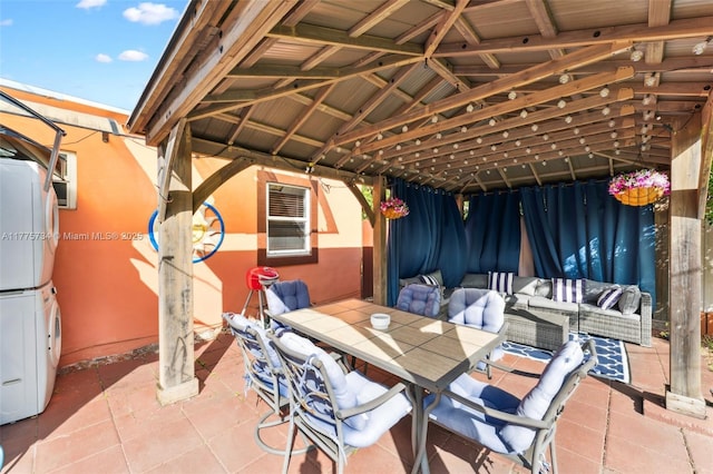 view of patio featuring an outdoor hangout area, stacked washer and clothes dryer, and outdoor dining area