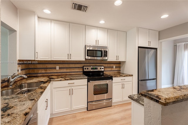 4291 S Pine Island Rd, Davie, FL 33328 - kitchen with stainless steel appliances, dark stone counters, decorative backsplash, white cabinets, and light wood-style flooring